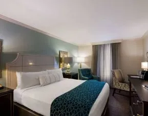 Double bed guest room in Royal Sonesta New Orleans, featuring television, armchair, and a workspace desk and chair.