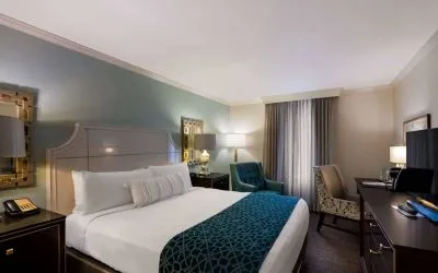 Double bed guest room in Royal Sonesta New Orleans, featuring television, armchair, and a workspace desk and chair.