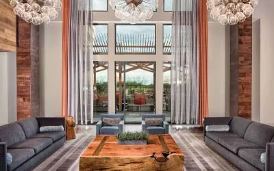 Sonesta Bee Cave Austin’s lobby lounge is furnished with armchair and sofa seating amid an airy setting, with the patio just steps away.