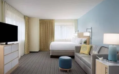 Sonesta ES Suites New Orleans double bed guest room, including large windows, sofa, and widescreen TV.