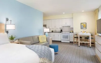 Double bed guest room in Sonesta ES Suites New Orleans, furnished with sofa and TV, plus kitchen area and dining table.