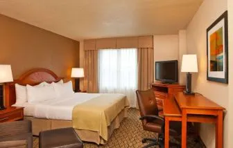 Double bed guest room in Sonesta Atlanta Airport South, featuring TV, window, and workspace desk and chair.