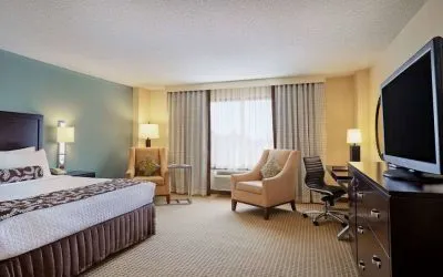 Sonesta Atlanta Airport North double bed guest room, including armchairs, window, and a television.