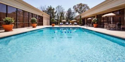 The hotel’s outdoor pool has potted plants by the side, in addition to shaded tables and chairs.