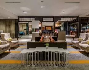 Sonesta Charlotte Executive Park’s lobby lounge is furnished with comfortable armchair and sofa seating for guests to relax and socialize.