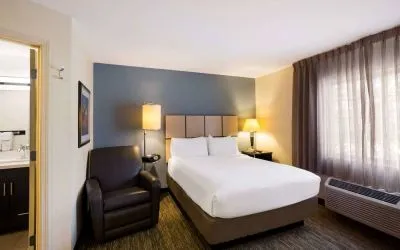 Sonesta Simply Suites St Louis Earth City double bed guest room, featuring armchair, window, and ensuite bathroom.