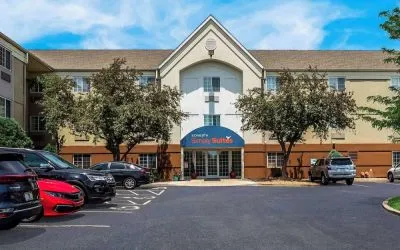 Sonesta Simply Suites St Louis Earth City’s exterior includes numerous parking spaces (including disabled spaces near the covered entrance) and trees.