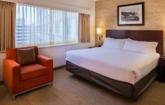 Double bed guest room in Sonesta Chicago O'Hare Airport Rosemont, including window, bedside light, and an armchair.