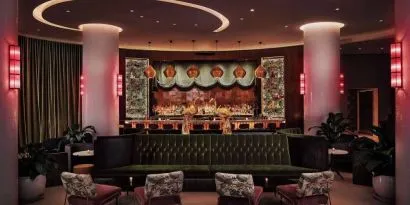 The lobby bar of Nautilus by Sonesta has a mix of traditional bar stool and more relaxed seating, numerous potted plants and subdued lighting.