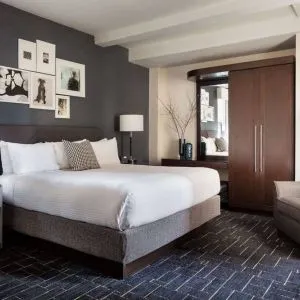 Double bed guest room in The Shelburne Sonesta New York, furnished with bedside lamp, wardrobe, and armchair.