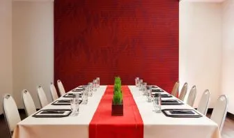Meeting room in The Shelburne Sonesta New York, furnished with long table, 10 chairs around it, and a stark white and red color scheme.