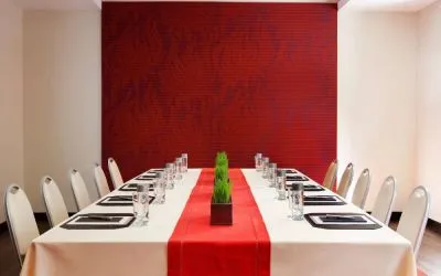 Meeting room in The Shelburne Sonesta New York, furnished with long table, 10 chairs around it, and a stark white and red color scheme.