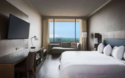 Sonesta Nashville Airport double bed guest room, including desk, chair, wall-mounted TV, and a sofa.
