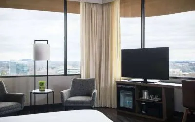 Sonesta Nashville Airport guest room, featuring widescreen television, chairs and a coffee table, and large windows.