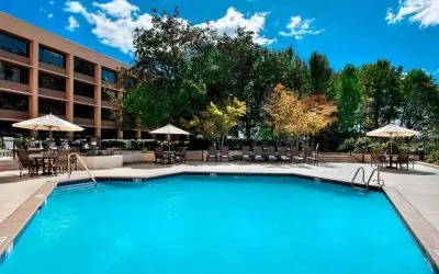 Sonesta Nashville Airport’s outdoor pool has shaded tables and chairs nearby, alongside a row of sun loungers.