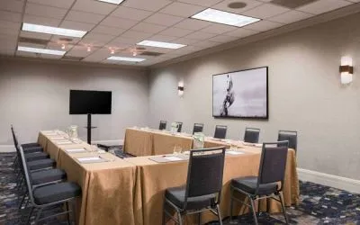 Meeting room in with tables arranged in a U-shape facing  large TV, plus a large artistic photograph of a horse on the wall.