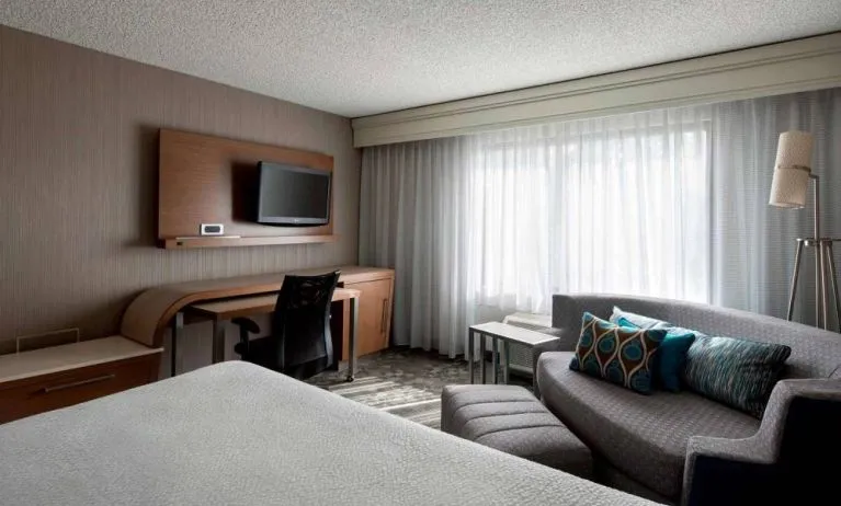Sonesta Select Tempe Downtown double bed guest room, furnished with TV and sofa, plus workspace desk and chair.