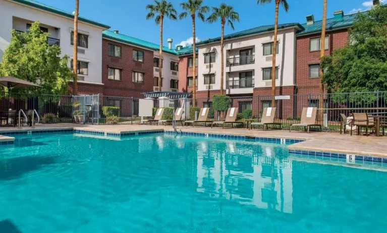 The hotel’s outdoor pool has loungers, as well as a table and chairs, by the side, plus towering trees beyond the fence.