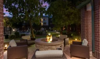 Sonesta Select Tempe Downtown’s fire pit is surrounded by armchairs, with trees nearby and the pool just steps away.