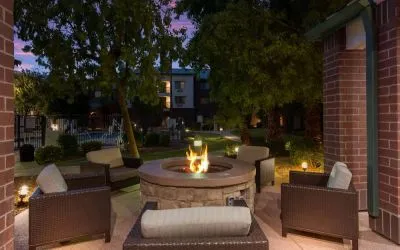 Sonesta Select Tempe Downtown’s fire pit is surrounded by armchairs, with trees nearby and the pool just steps away.