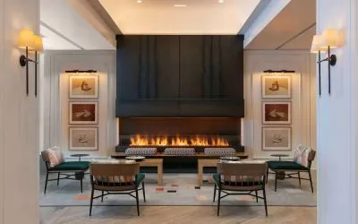 The lobby lounge of Royal Sonesta Chicago Downtown is furnished with comfortable seats and coffee tables close to a fireplace, with art on the walls.