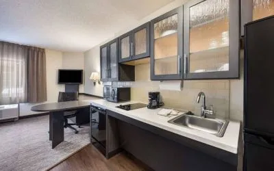 Sonesta Simply Suites Phoenix Tempe guest room kitchen, with hob, microwave, oven, and fridge-freezer, and a nearby TV.