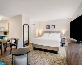 Double bed guest room in Sonesta ES Suites Denver South - Park Meadows, with TV and kitchen, between which is a table and chairs.