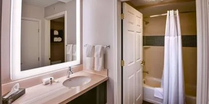 Guest bathroom in Sonesta ES Suites Fort Lauderdale Plantation, with shower-equipped bath, lavatory, mirror, and sink.