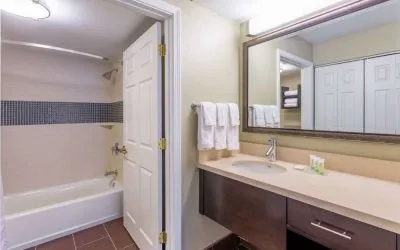 Guest bathroom in Sonesta ES Suites Atlanta - Perimeter Center, with shower and bath, sink and mirror.