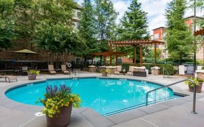 Sonesta ES Suites Atlanta - Perimeter Center’s round outdoor pool has potted plants and sun loungers nearby, with tables and chairs close at hand.