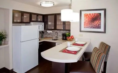 Sonesta ES Suites Atlanta Alpharetta Avalon guest room kitchen, including fridge-freezer, microwave, and kitchen table with two chairs.