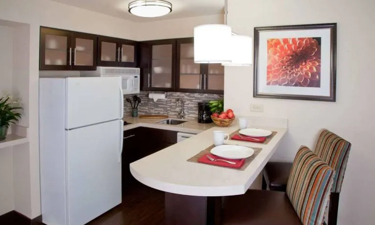Sonesta ES Suites Atlanta Alpharetta Avalon guest room kitchen, including fridge-freezer, microwave, and kitchen table with two chairs.