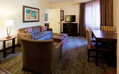 Sonesta ES Suites Atlanta Alpharetta Avalon guest room living area, furnished with sofa, armchair, table and chairs, and a TV.