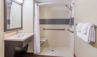 Guest bathroom in Sonesta ES Suites Atlanta Alpharetta Avalon featuring shower with curtain, mirror, and sink.