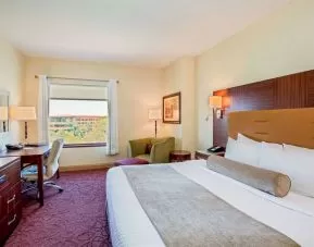 Sonesta Milwaukee West Wauwatosa double bed guest room, including armchair, TV, desk, chair, and window.