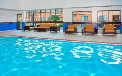 Sonesta Select Detroit Auburn Hills’ indoor pool has armchair and sofa seating by the side, plus large windows.