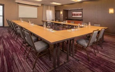 Meeting room in Sonesta Select Columbia, with tables arranged in a U-shape, seating for over a dozen attendees, and a whiteboard.