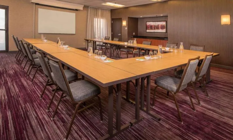 Meeting room in Sonesta Select Columbia, with tables arranged in a U-shape, seating for over a dozen attendees, and a whiteboard.