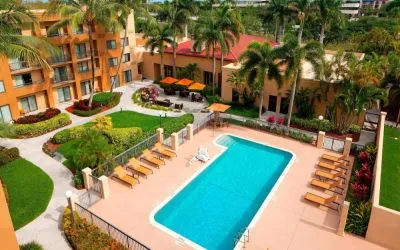 Sonesta Select Boca Raton’s outdoor pool is equipped with a lift, and has sun loungers by the side plus pleasant greenery beyond the fence.
