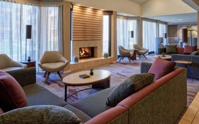 The lobby lounge in Sonesta Select Indianapolis Carmel has a mix of comfy chairs and large sofas, plus coffee tables and a fireplace.