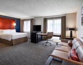 Sonesta ES Suites Annapolis double bed guest room living area, featuring windows, sofa, TV, and a desk and chair.