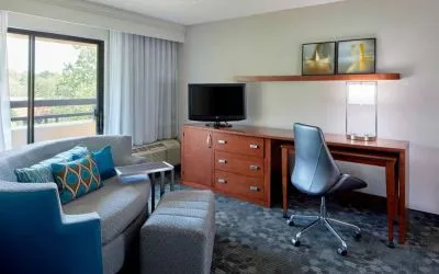 Sonesta Select Raleigh Durham Airport Morrisville guest room living area, furnished with workspace desk and chair, and a sofa and TV.