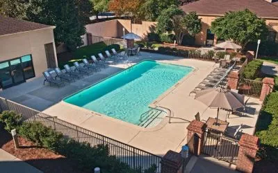 The outdoor pool at Sonesta Select Raleigh Durham Airport Morrisville has sun loungers by the side, as well as shaded tables and chairs.