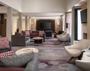 Lounge in the hotel lobby, furnished with comfy chairs and large sofas, coffee tables and multiple large televisions.