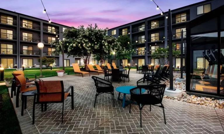 Sonesta Select Philadelphia Airport’s patio features a brickwork surface, tables and chairs, sun loungers, and pleasant trees nearby.