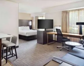 Double bed guest room in Sonesta ES Suites Raleigh Cary, featuring TV and sofa, plus workspace desk, chair, and lamp.