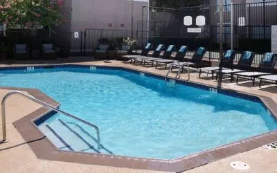 Sonesta ES Suites Dallas Medical Market Center’s outdoor pool has sun loungers as well as armchairs and coffee tables by its side.
