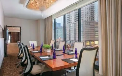 Hotel meeting room, with long wooden table, eight swivel chairs, and floor-to-ceiling windows.