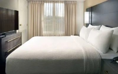Double bed guest room with a window and large TV at Sonesta ES Suites Raleigh Durham Airport Morrisville.