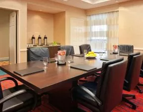 Hotel meeting room with long wooden table, large window, and eight leather chairs.